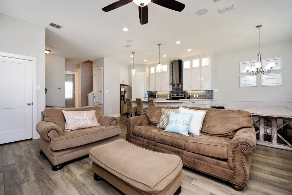 Sink into plush leather sofas in your spacious open-concept living area, where coastal charm meets modern comfort beneath soaring ceilings.
