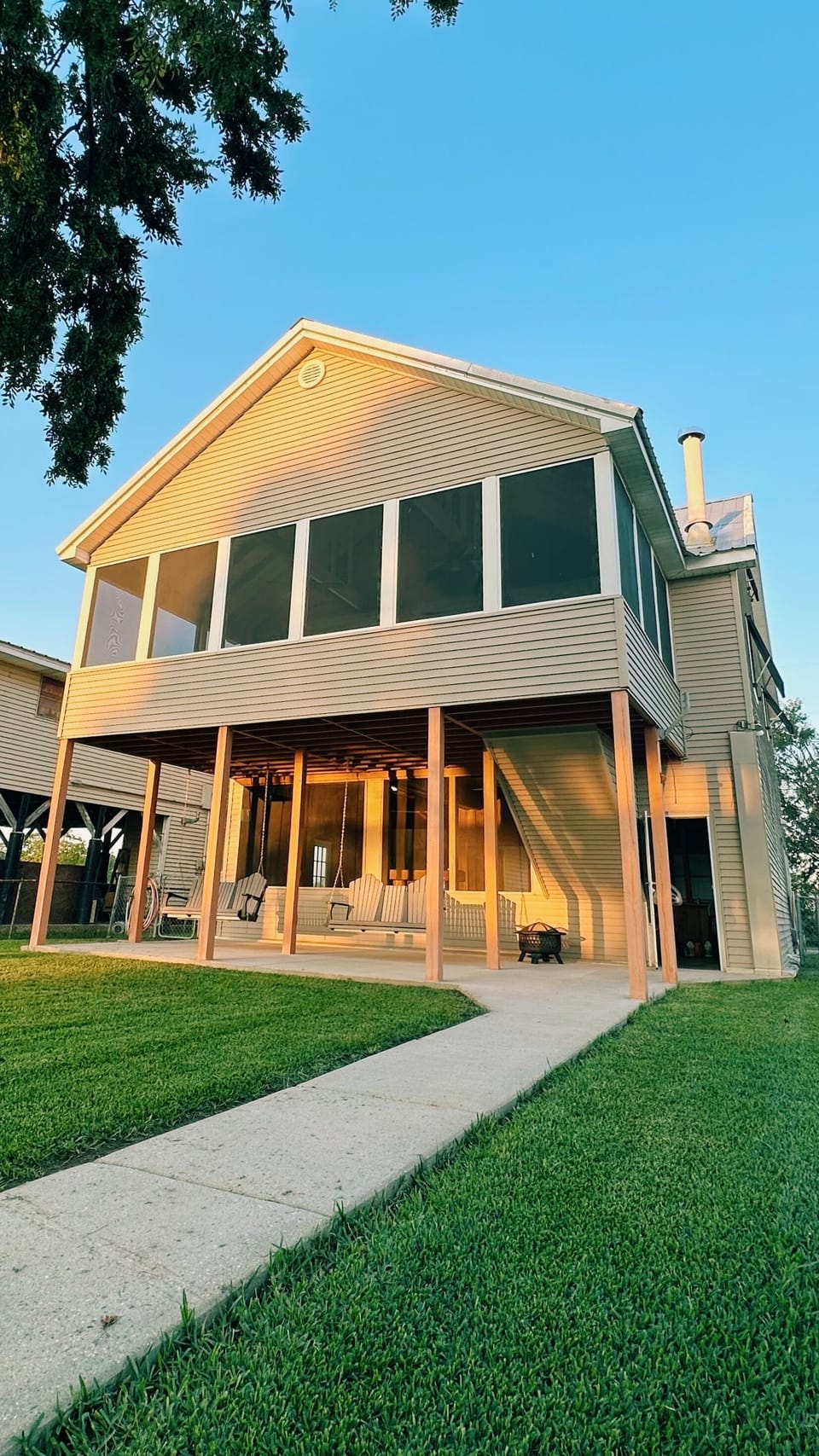 Modern elevated lake house with a spacious porch and open lawn.