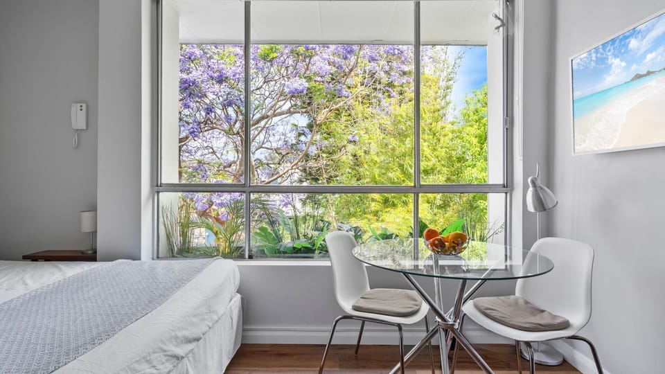 Dine with a view in this bright, cheerful corner, featuring a sleek glass table and a stunning backdrop of lush, flowering trees