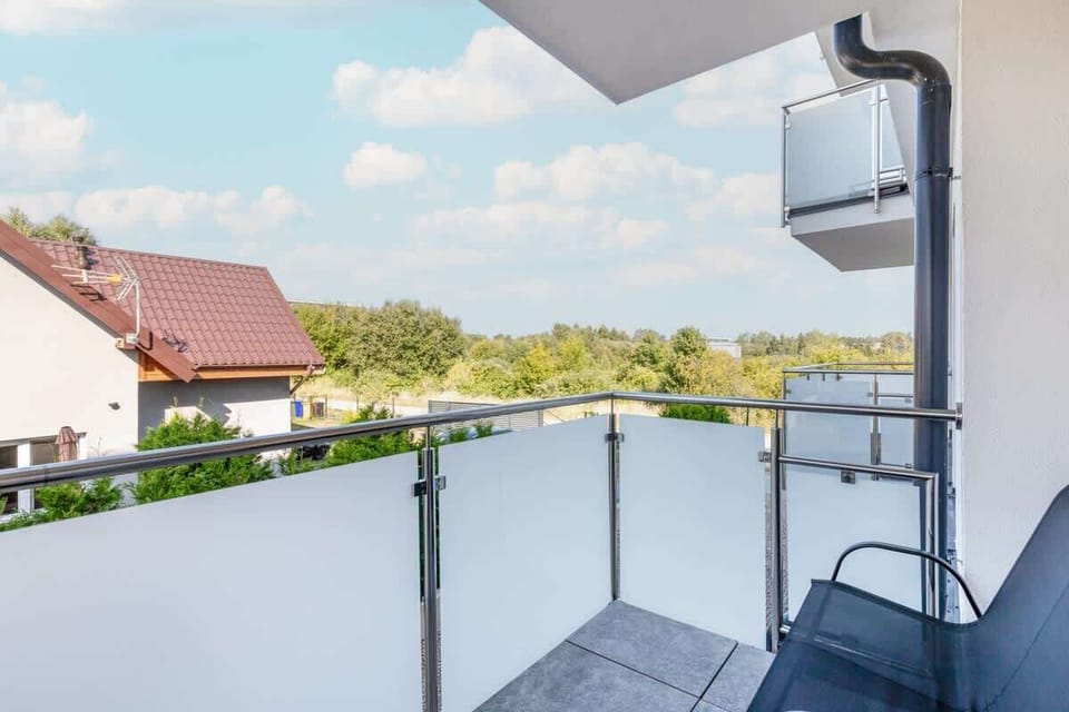 A view from a balcony overlooking rooftops and trees. Peaceful and scenic, ideal for a relaxing moment.