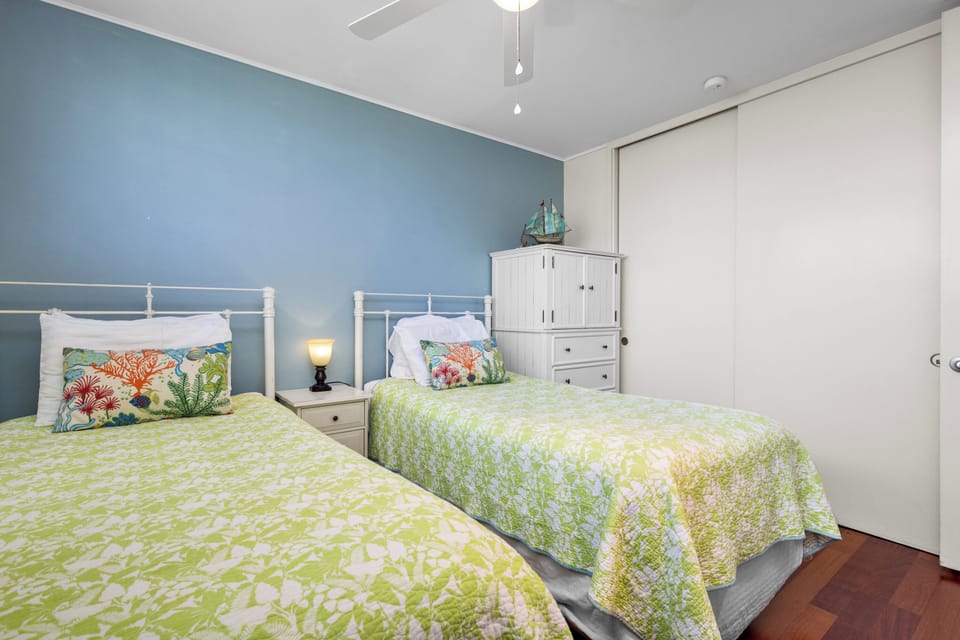 Drift off in this cheerful coastal bedroom with crisp linens, soothing blue walls, and twin beds perfect for family or friends sharing your beach escape.