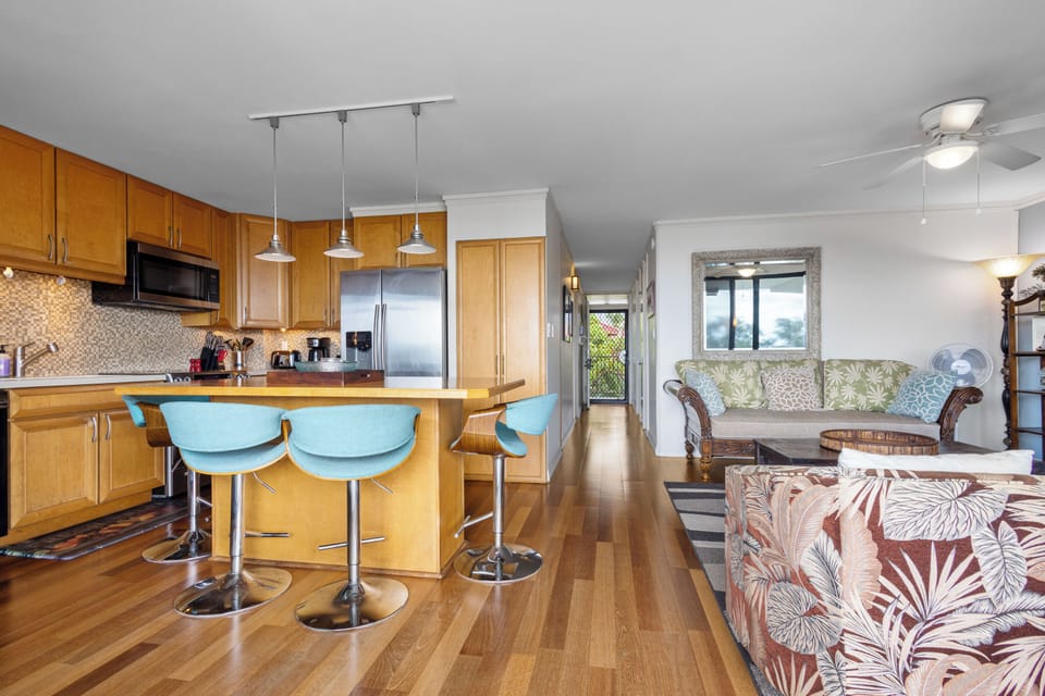 Gather around the kitchen island for morning coffee or relax in the open living area, where tropical-inspired furnishings and warm wood floors create your home away from home.