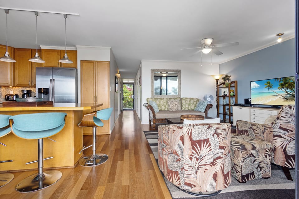 Your open-concept haven blends coastal charm with comfort—tropical prints, warm wood tones, and beach-inspired art create a relaxed island vibe perfect for unwinding after a day exploring.