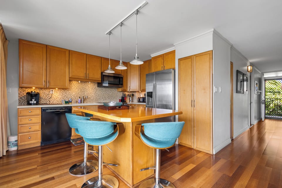 A bright, fully-equipped kitchen awaits with warm wood cabinetry, modern appliances, and an inviting breakfast bar where you can savor morning coffee or plan your day's adventures.