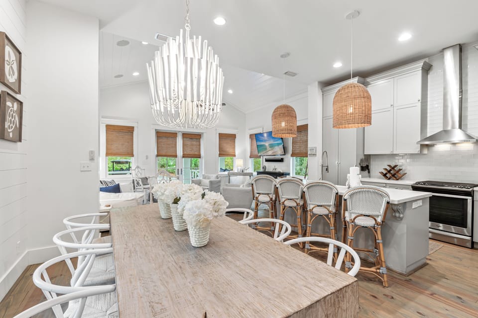 Gather around this stunning open-concept kitchen and dining space, where white cabinets meet warm wood tones for your perfect coastal getaway.