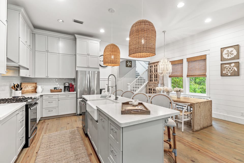 Your spacious chef's kitchen invites culinary adventures with gleaming countertops, premium appliances, and warm wicker pendant lights creating the perfect cooking atmosphere.