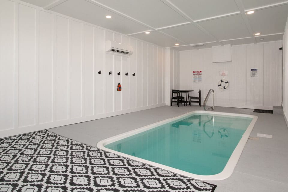 Dive into comfort in this bright and airy indoor pool area, complete with a cozy seating space and modern finishes.