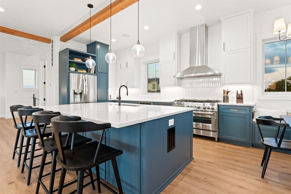 Chef's kitchen with counter seating at island, commercial ice maker, drawer microwave, toaster, dishwasher, refrigerator/freezer, gas stove w/ griddle