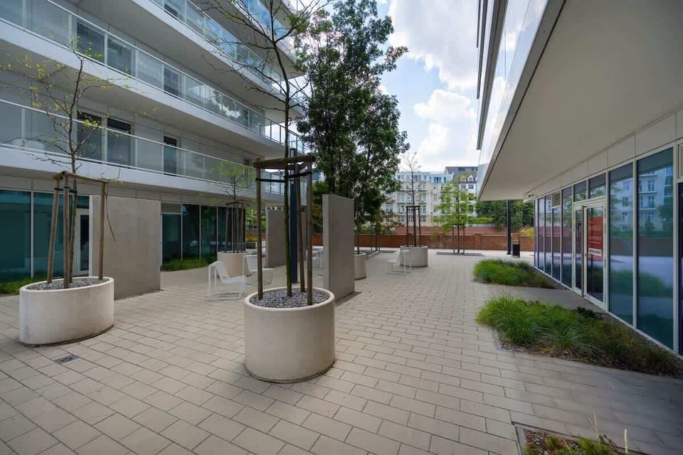 A street-level view of a contemporary apartment complex. Includes retail units and wide sidewalks for convenience.

