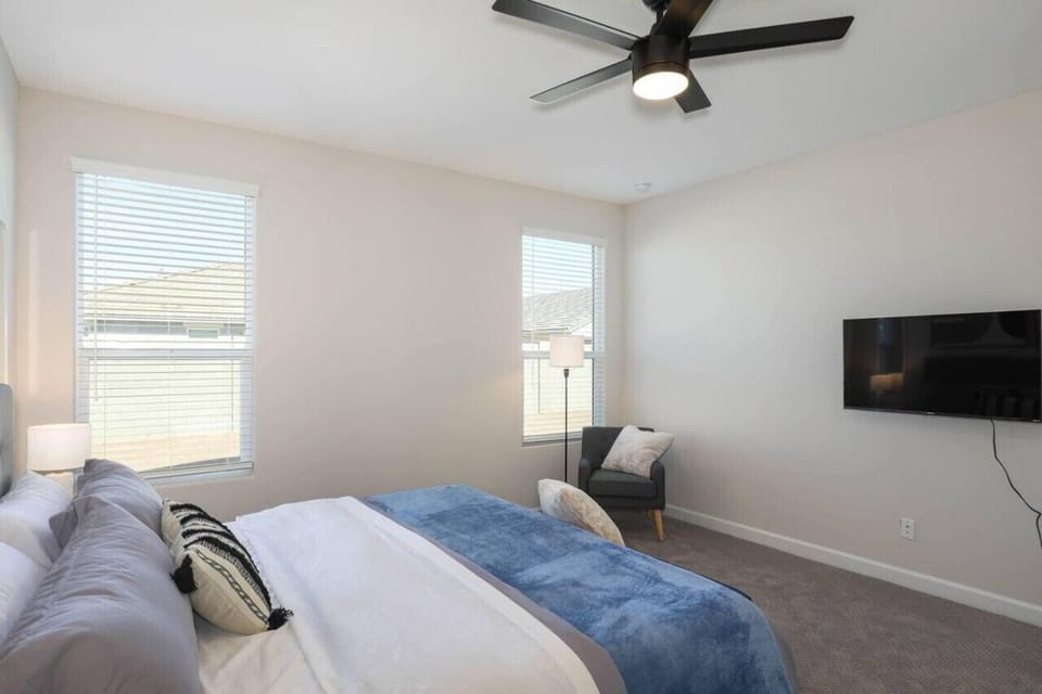 Unwind in the comfortable primary suite featuring a king-size bed, mounted TV, and plenty of natural light.