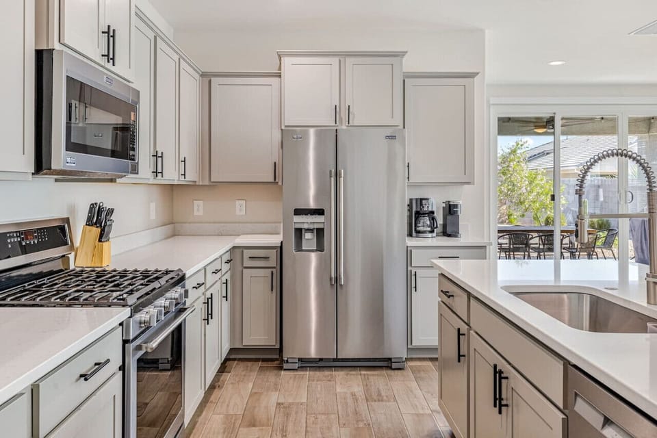 Fully equipped gourmet kitchen featuring stainless steel appliances, sleek cabinetry, and a spacious island for meal prep and dining.