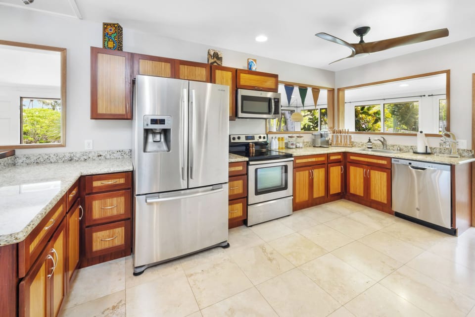 The kitchen comes fully equipped with stainless steel appliances and plenty of counter space, ideal for preparing meals with a view of the garden.