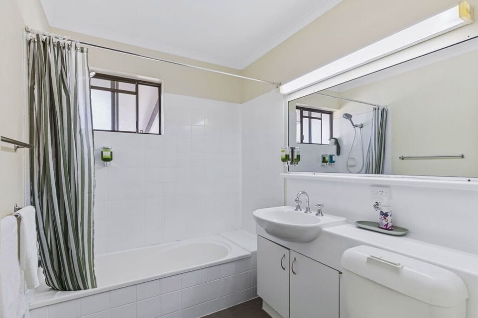 Clean, well-lit bathroom with bath, shower, and plenty of counter space.