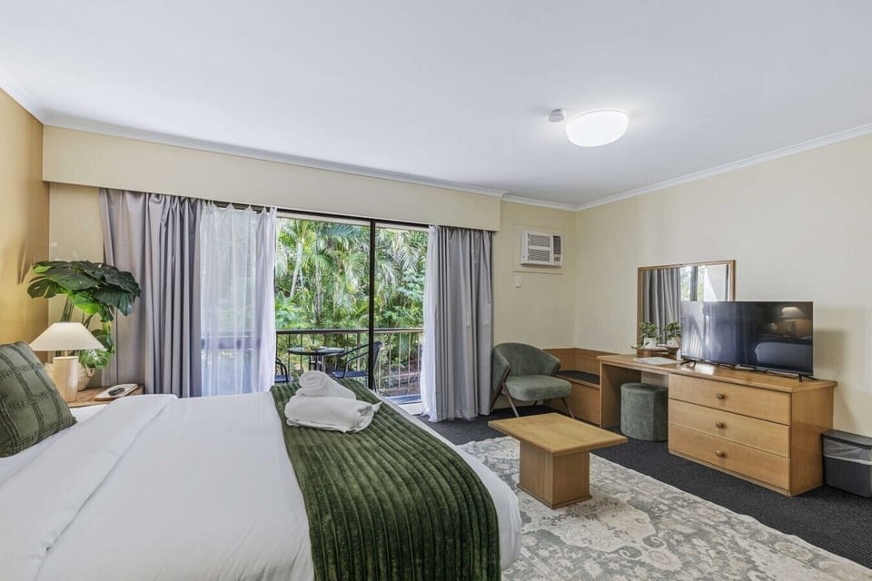 A bright, comfortable bedroom with direct balcony access and garden views.