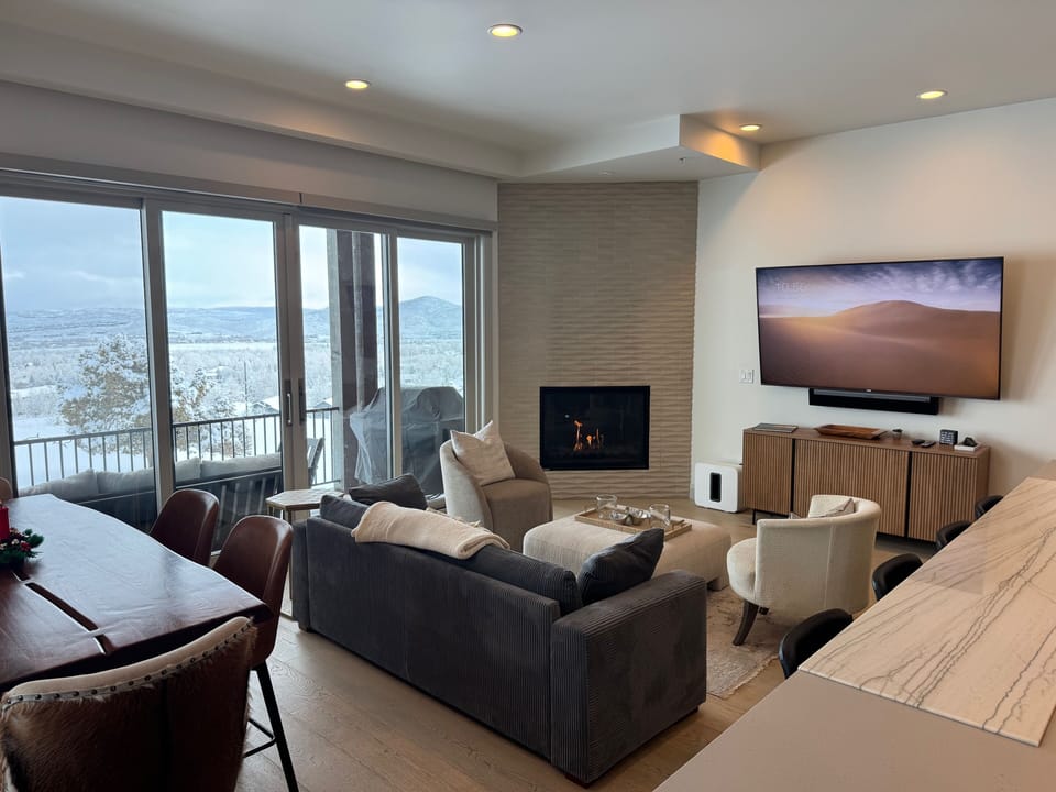 Spacious open living area with floor-to-ceiling windows, cozy seating, and beautiful mountain views.