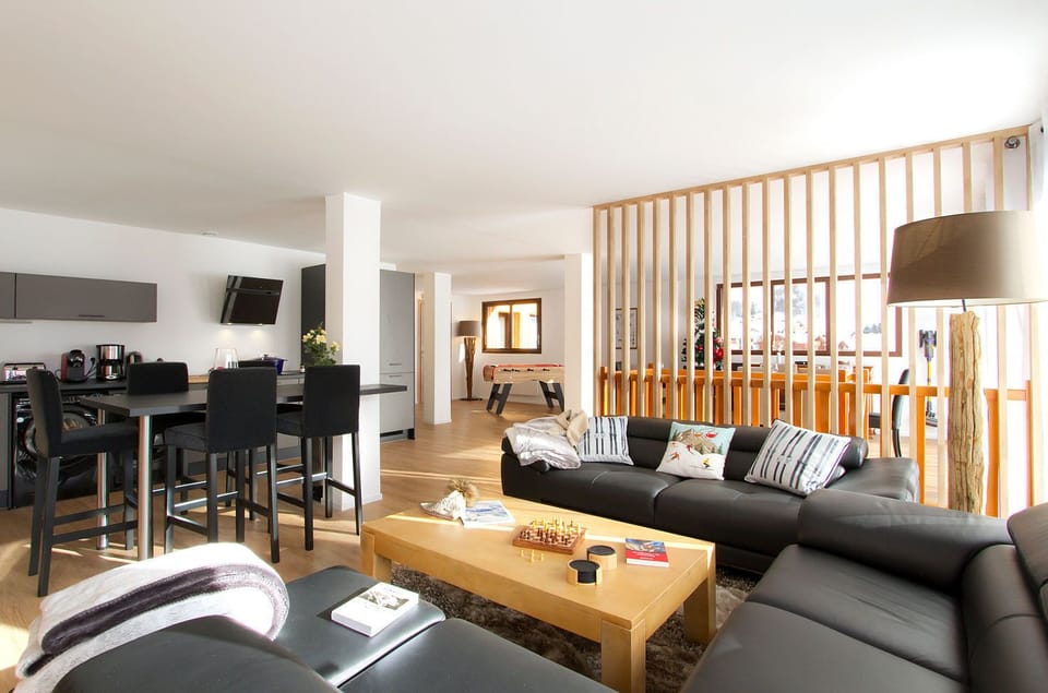 This modern, open-plan living space is perfect for gathering with loved ones. Comfortable seating, a large TV, and beautiful wooden detailing create a warm and inviting atmosphere.