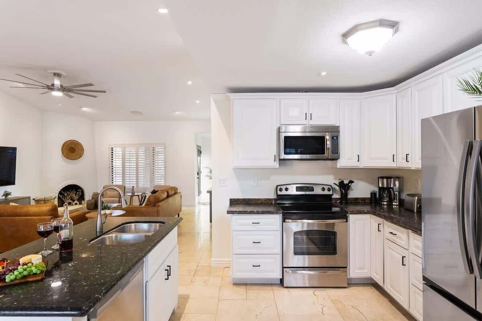 A fully equipped open-floor kitchen stocked with your basic cooking essentials, stainless steel appliances, dining room table, breakfast table.