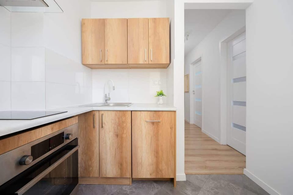 A galley-style kitchen layout with wooden cupboards and tiled flooring. Ample storage and modern design make it functional.