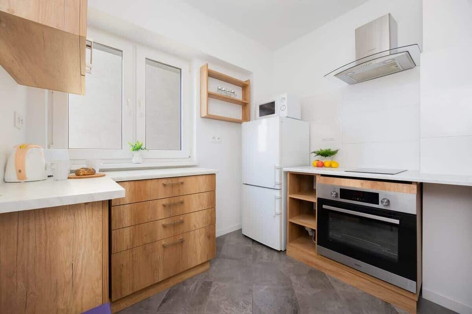 A modern kitchen with wooden cabinets and white walls. Appliances are built-in and stainless steel for a sleek look.