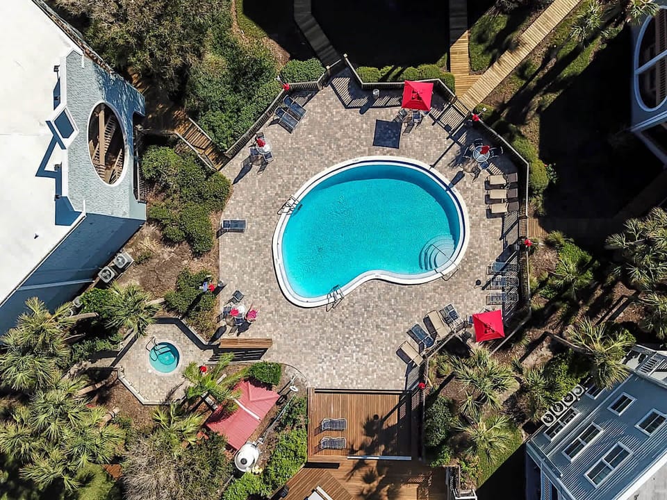 - Top-down aerial shot of pool with umbrellas and seating  
- Spacious pool deck surrounded by palm trees and greenery  
- Perfect view of community amenities and resort design  