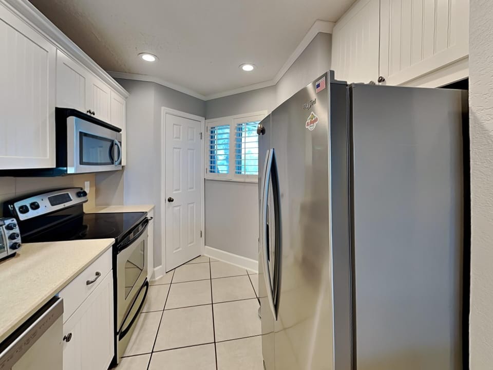 - Cook up your favorites in a sleek kitchen with stainless steel appliances and microwave
- White cabinetry and crown molding give the space a bright coastal finish
- Tile flooring and recessed lights keep it clean and functional