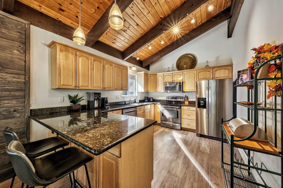Gather around this stunning granite island where rustic beams meet modern appliances, creating your perfect mountain kitchen retreat.