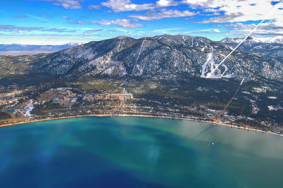 Aerial view of a stunning lakeside mountain town with snow-capped peaks and pristine turquoise waters.
