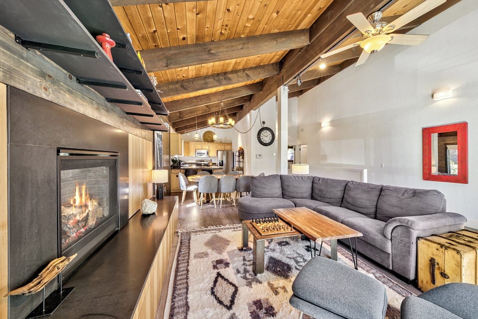 Cozy up in your spacious living room with exposed beams, crackling fireplace, and plush sectional sofa perfect for evening relaxation.