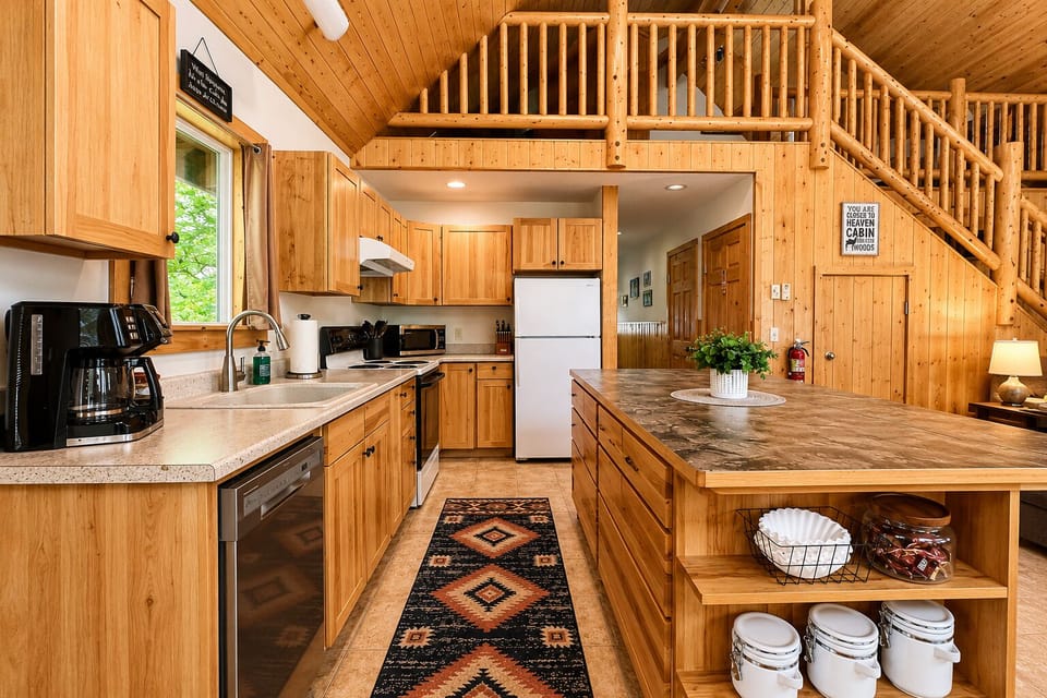 Gather around the expansive island in this fully-equipped, open-concept kitchen—your perfect spot for cooking together, sharing stories, and savoring meals beneath soaring wood-beam ceilings that make every moment feel cozy and special.