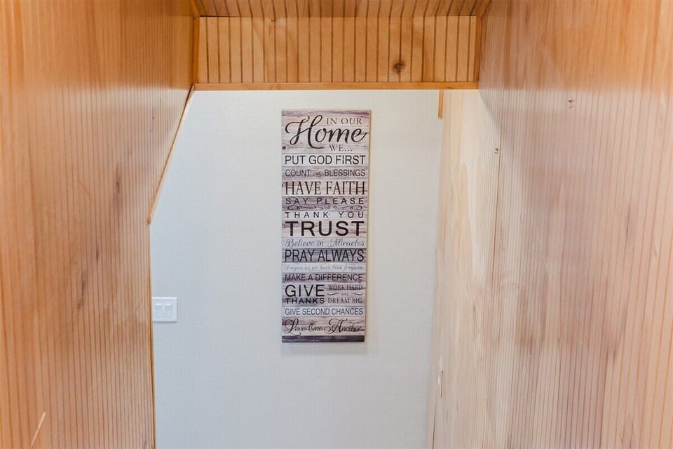 Interior hallway with inspirational wall décor and rustic wood paneling.