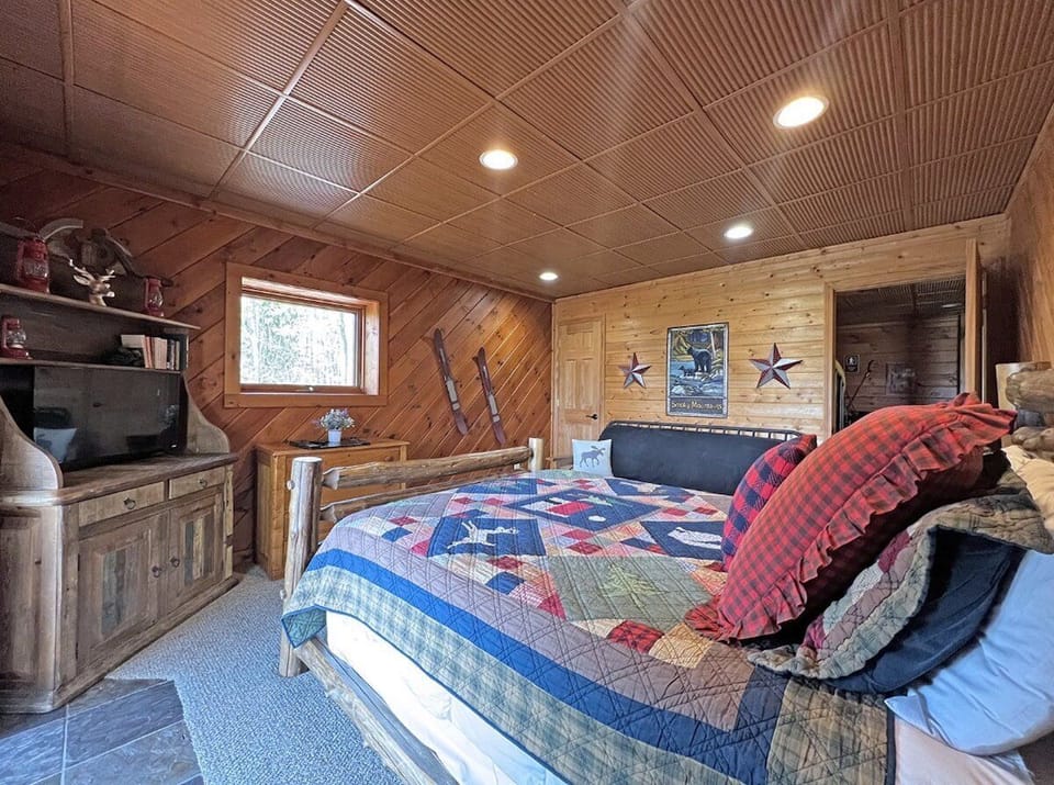 Rustic bedroom with wood-paneled walls, a patterned quilt bed, and mountain cabin décor. Cozy sleeping accommodations at High Haven near Bryson City in the Smoky Mountains.