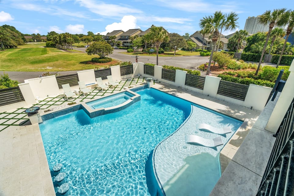 Stunning private pool and hot tub, perfect for relaxing after a day at the beach. Lounge in the sun with palm trees and peaceful surroundings, offering a true escape right outside your door.