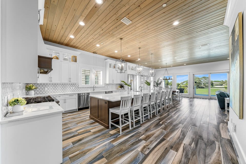 GOURMET, FULLY-STOCKED KITCHEN: Cook in style with upscale appliances, custom cabinetry, and a marble-topped entertainment bar, all beneath beautiful brass chandeliers