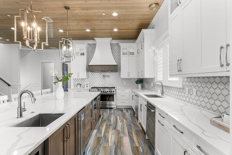 GOURMET, FULLY-STOCKED KITCHEN: Cook in style with upscale appliances, custom cabinetry, and a marble-topped entertainment bar, all beneath beautiful brass chandeliers