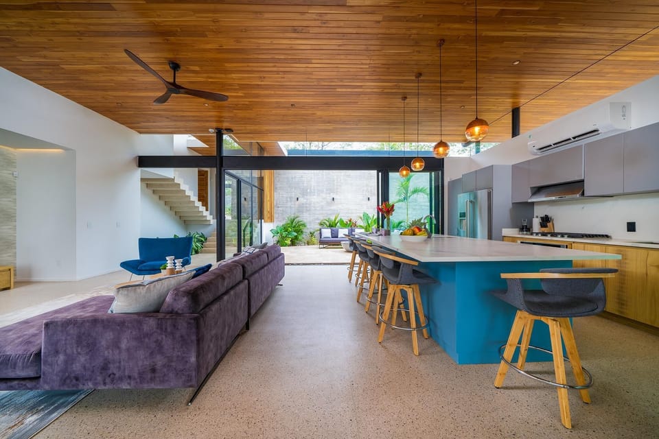 Indoor social area, kitchen, and entry to the outdoor lounge/firepit in the background