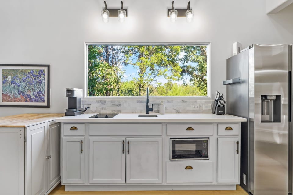 The kitchen features a large fridge, stove, microwave, and coffee machine