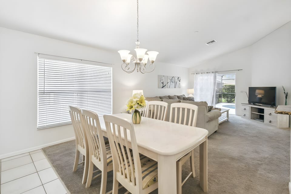 This bright and airy dining area boasts a spacious table with elegant wooden chairs, ideal for gathering with loved ones. Natural light pours through large windows, enhancing the light decor and creating a cozy ambiance.