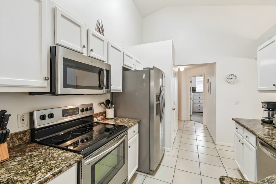 Welcome to a bright kitchen with sleek stainless steel appliances and elegant granite countertops, ideal for culinary adventures. The warm white cabinetry and tiled flooring create a cozy atmosphere for you to relax and enjoy.