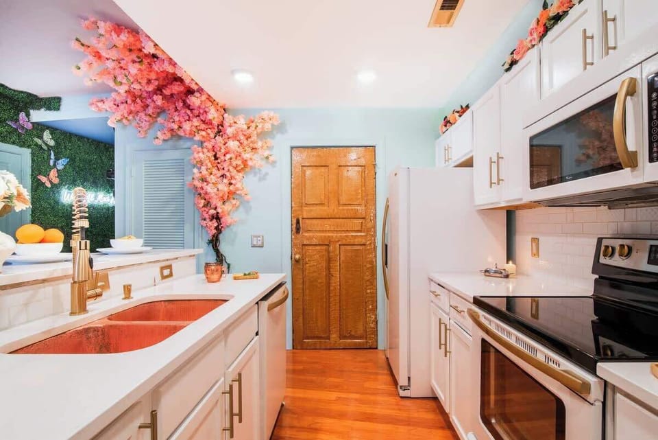 Sleek kitchen with white cabinetry, copper accents, and cherry blossom details. Fully equipped and thoughtfully renovated, blending modern style with everyday comfort for Uptown Charlotte mid-term stays.