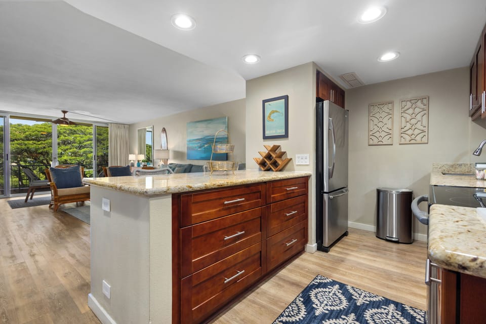 Your open-concept retreat seamlessly blends the kitchen and living space, where rich wood cabinetry, granite counters, and modern appliances invite you to cook and gather with ease.
