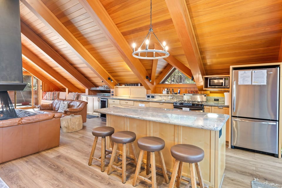 Gather at your spacious kitchen island with mountain-style bar seating, where vaulted wood ceilings and natural light create a warm, inviting space for cooking and conversation.