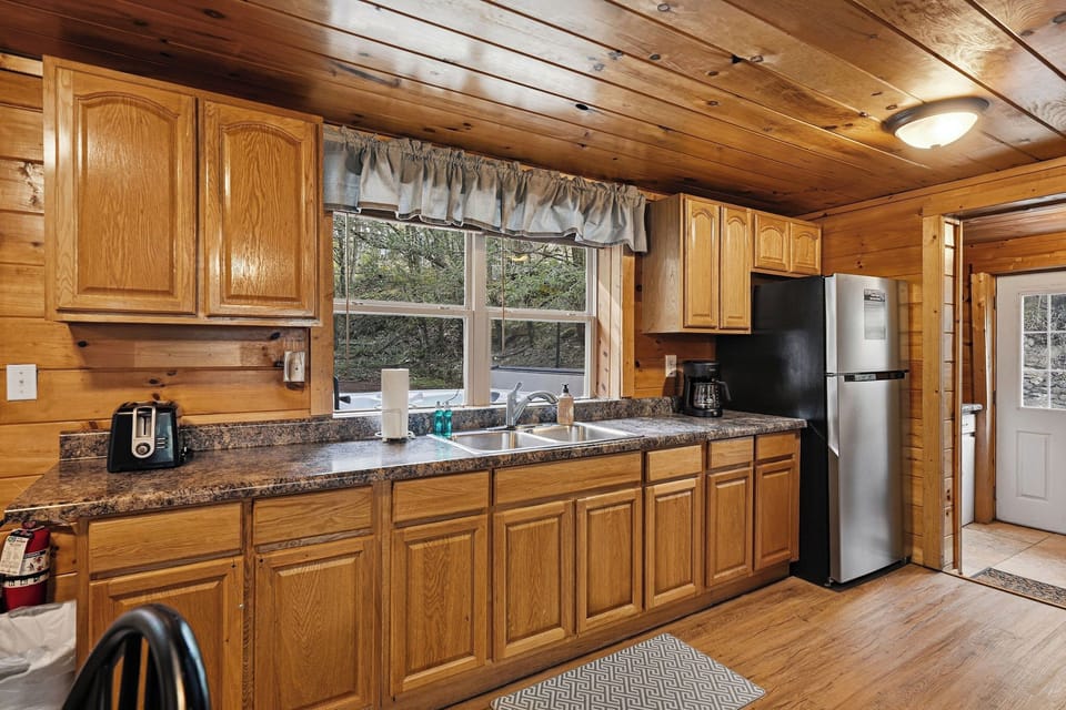 Your fully-equipped kitchen features granite countertops, oak cabinets, and modern appliances with natural light streaming through the window.