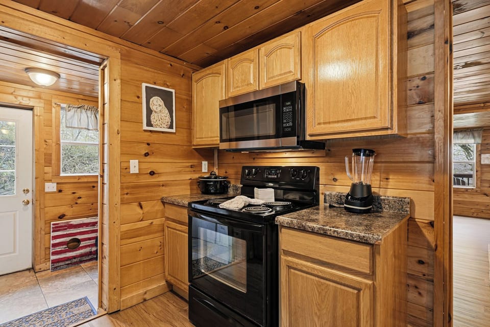Your rustic cabin kitchen features warm wood walls, granite counters, and modern appliances for memorable mountain meals.