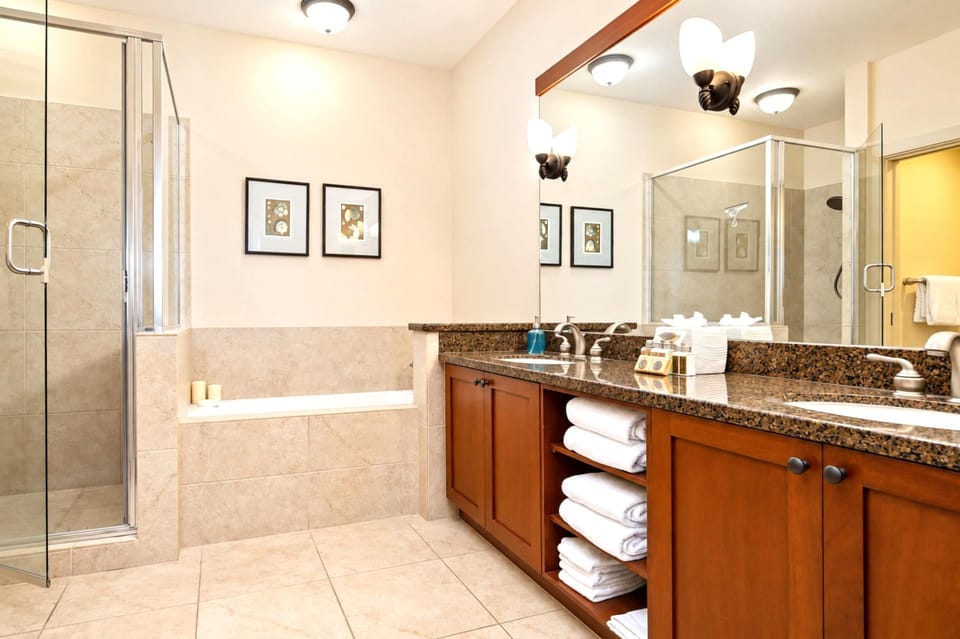 Primary ensuite bath at Halii Kai HLI-12A — dual vanity, soaking tub, and a separate glass-enclosed shower