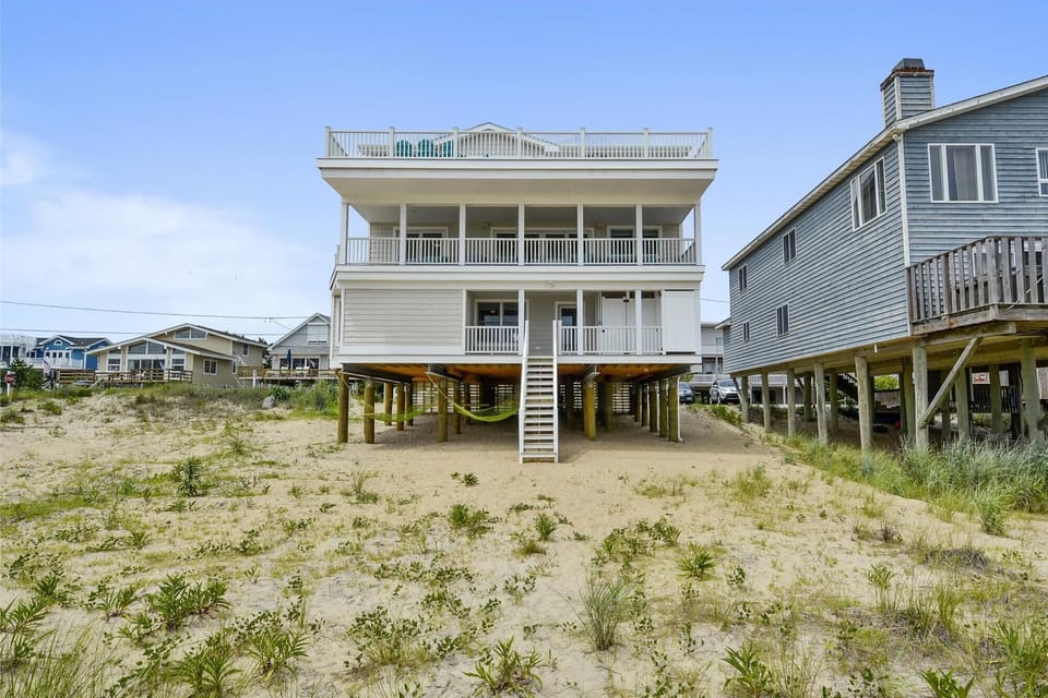Three-story beachfront structure positioned directly on sandy shoreline, offering convenient access to coastal surroundings and elevated decks for enjoying the seaside setting.