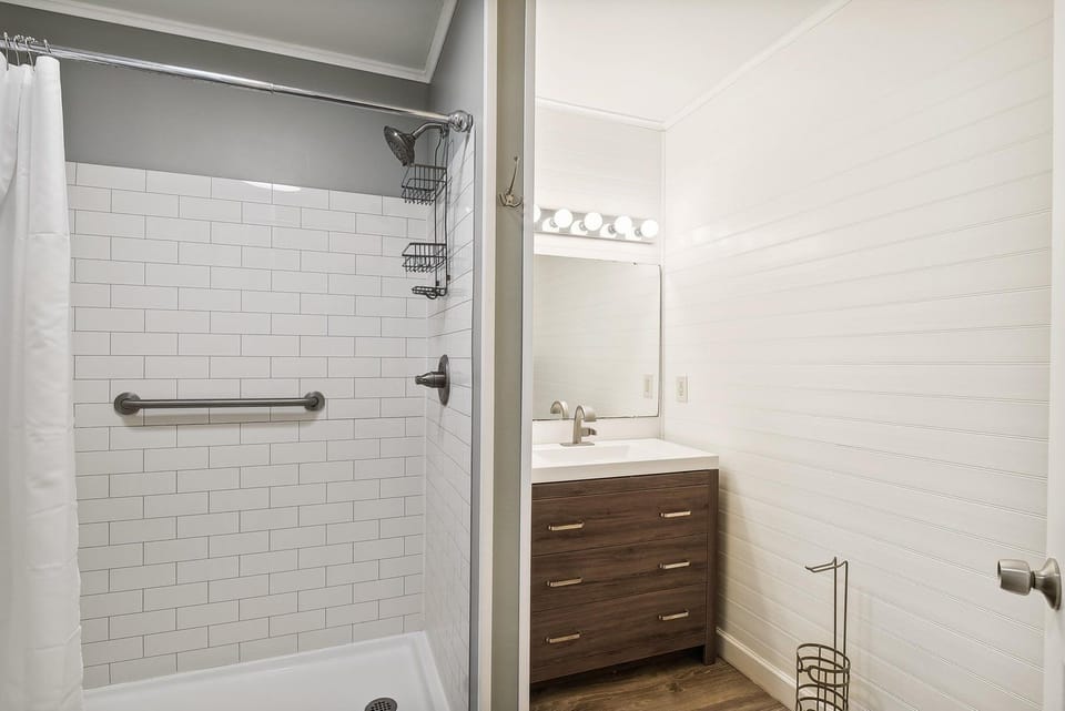 Step into your fresh, modern bathroom with a spotless tiled shower and stylish vanity. Crisp white subway tile and warm wood tones create a welcoming retreat after a day of exploring.