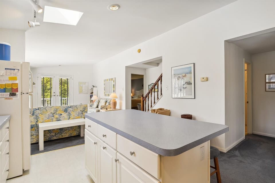 Bright, open kitchen flows seamlessly into your inviting living space, where natural light pours through the skylight and French doors, creating a warm, welcoming atmosphere for relaxation and gathering.