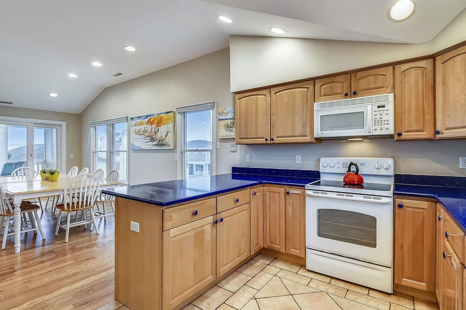 Cook up your favorite meals in this bright, spacious kitchen with stunning blue countertops, modern appliances, and coastal views through sunlit windows.