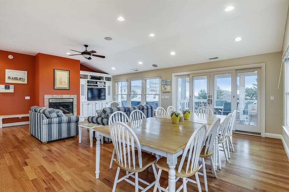 Gather around the farmhouse-style dining table with seating for twelve, where sunlight pours through French doors, opening to your private balcony overlooking serene water views.