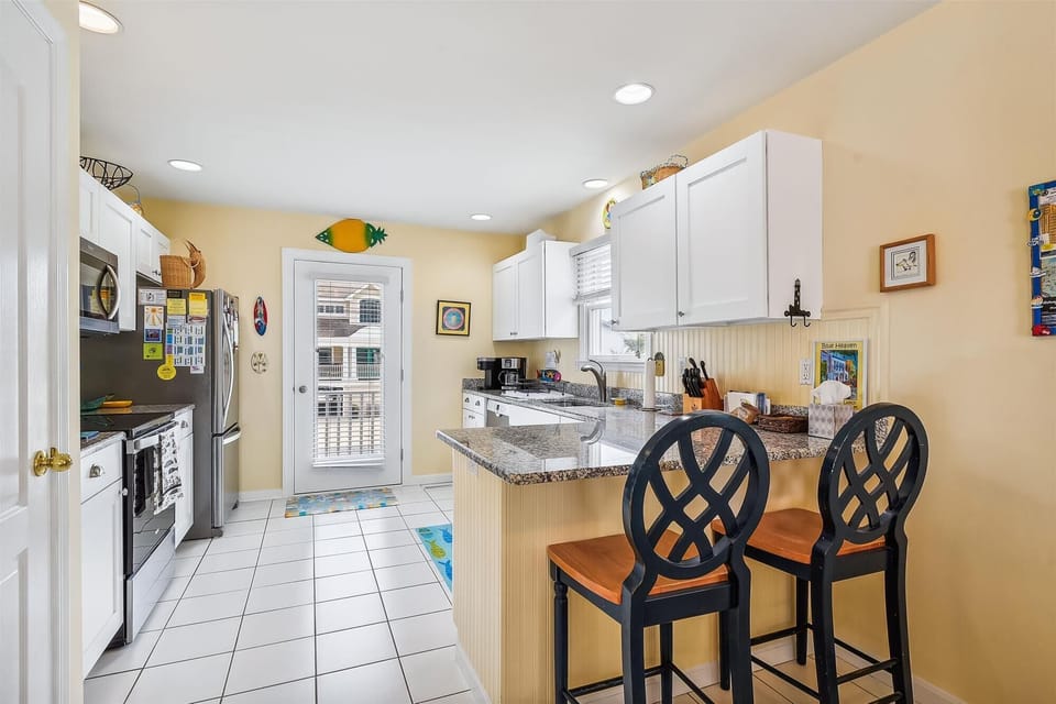 You'll love preparing meals in this bright, cheerful kitchen with modern appliances, granite counters, and a cozy breakfast bar with stylish seating—perfect for morning coffee or casual dining.